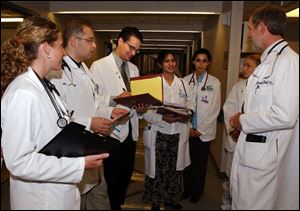 Dr. Roland Skeel, right, talks with Medical College of Ohio students and residents while making his hospital rounds.