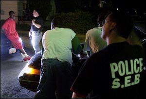 Detective Bill Noon, left, questions a young man at Lincoln Avenue and Ray Street, while Detective Keith Zaborowski monitors others at the scene. Both are with the Gang Task Force.