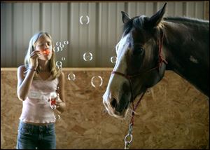Tiffany Towell, 12, blows bubbles at Makona