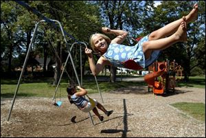 Chelsey Gray, in polka dots, and Ashlee Hartsfeld have fun on swings that often break down.