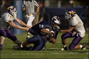 Woodward running back Khalfani Rice (32) is hauled down by Waite defenders Allen Fitch (14) and Mike Lucas (1), but Rice finished with 166 yards on 31 carries.
