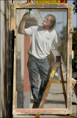 ROV framed 01 - John Ortyl, an overall handyman and painter, does some odd jobs for Bijou owner Kip Diacou as he paints some of the frames of the dispalays on the outside of the nightclub on Superior St. The Blade/Allan Detrich