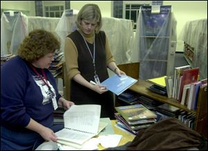 Library preservationist Irene Martin examines water-damaged books with Nancy Eames, manager of the children's section that suffered water damage after a fire on the floor above.