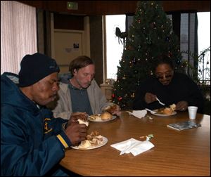 From left, Keith Purifie, Denny Bocian, and Michael Welch share a meal at Just As I Am Christian Church in downtown Toledo on Madison Avenue.