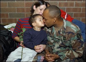 Sgt. Donnale Williams kisses Donnale, Jr., 2, as his wife Katherine and son Christopher, 11 (partially hidden), look on during a ceremony at Owens Community College yesterday for departing members of the 216th Engineer Battalion, Company C. Sergeant Williams departs for the Middle East later this month.
