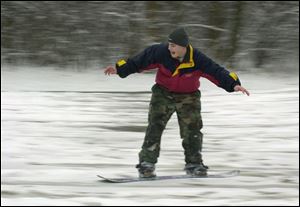 Ryan Scanlan of Northwood cruises down a hill in Pearson Metropark on his brother s new snowboard.