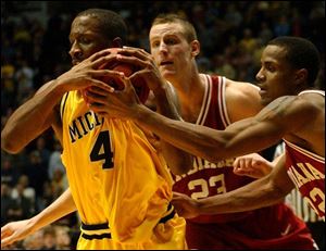 Michigan s Daniel Horton, left, tries to hold onto the ball while being defended by Indiana s Sean Kline, center, and Marshall Strickland.