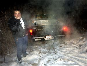 Bill Heinemann of Woodville waits for his pickup to be towed out of a ditch on I-75 northbound near Sterns Road in Erie Township, Michigan.