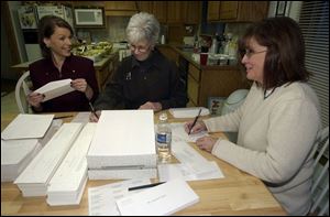 INVITATION ONLY: Cynthia Ford, left, Kathy Holmes, and Candace Morel sign, stamp, and stuff invitations in Mrs. Morel's home for Mom's Nite Out 2004.