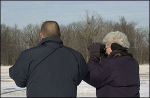 Volunteers Vic and Lois Harder of Oak Harbor look for an eagle near the nest in a tree in the background.