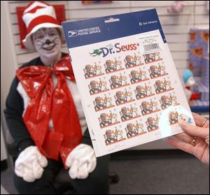 CTY CAT03P 2 3/3/04 PHOTO BY LORI KING The Cat in the Hat (Colleen Reese, a Maumee Post Office branch supervisor) hands a card of stamps for sale to a customer to look at. She entertained kids and adults at the Maumee post office all day.