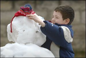 ROV snowman 01 - Samuel Pardi, 6, puts the the finishing touches on the snowman he and his mother Jodi made int he front yard of their Wood Street in Fremont. Allan Detrich/The Blade