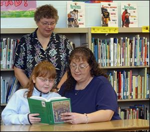 Sarah Sager, with mother Cari, had trouble reading, but now likes to read. Facilitator Cindy Kline listens.