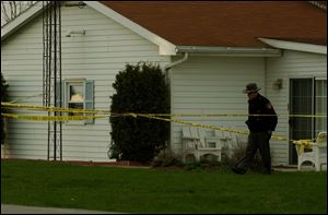 A Hancock County sherrif's deputy inspects the property where a Cass Township woman was found dead in her home.