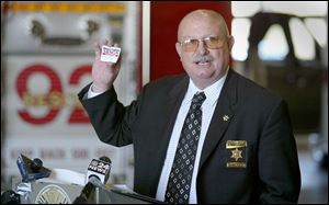 Ohio state fire marshall Tom Huston displays one of the cards arson investigators leave at the scene of a suspicious fire to urge witnesses, such as Robbie Ward, of Fostoria, to come forward with information needed to arrest and charge arsonists.