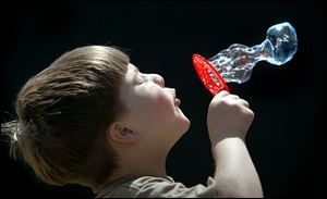 ROV bubbles 01 - Kenny Spence, 6, blows bubbles in the bright sun of a spring day that is finally fit for short shirt sleves, under the watchful eye of his mother Tammy, on lincoln St. in Findlay. Allan Detrich/The Blade