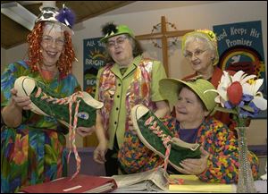 Gloria Parker (left) and Ruby Burkey hold size 18 shoes that belong to Yuk Yuk the clown, who will be part of their Bright Sunday celebration. Donna Mohn (back left) and JoAnn Diefenthalaer look on.
