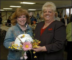 HARD HAT, SOFT TOUCH: Cyndy Meacham, left, and Deb Vas admire Ms. Vas' flower-bedecked hard hat at the Aurora Gonzalez Family Center.
