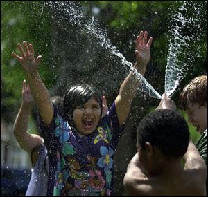 ROV COLD RELIEF 5/9/04 PHOTO BY LORI KING Kennedy Rios, 9, gets a blast of cold water from neighbor Stephan Robinson, 6, as they play with a hose on Colton St. in Toledo.