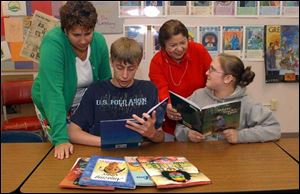 Idali Feliciano, center rear, director of Cambios, and eigth-grade teacher Ruth Lyons, left, help students Justin Fetzer and Amber Martin at Adrian's Sand Creek school with their reading. 