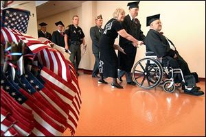 Robert Charvat, right, leads veterans receiving high school diplomas at a ceremony at University of Toledo's Nitschke Hall.