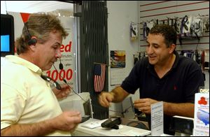 Steve Mourad, right, assists Rick Dusseau with a headset at Page Plus Communication.