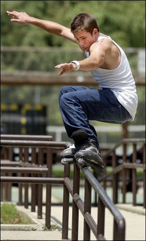 ROV July 6, 2004 - Mike Currier, 22, of Toledo, lands on one rail after jumping from another at Jermain Park Tuesday afternoon.  He and two friends were practicing their inline skating.  Mike says he is on the K2 Skate international amateur team.  K-2 Corp.  sells a variety of products including skates, he says.  Blade photo by Dave Zapotosky