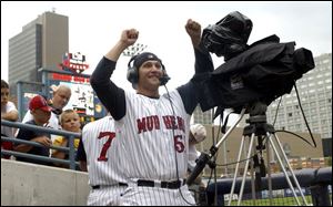 Hens pitcher Shane Loux checks the other side of a television camera during the rain delay.