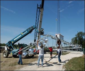 Volunteers put up the last light for the stadium. In the background with the press box on top are the home team's stands.