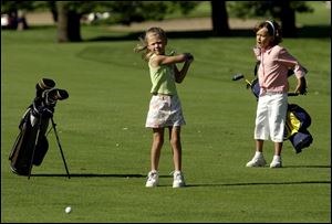 Abby Kalucki, 6, hits a fairway shot as Morgan Hall, 6, watches. The girls were playing during a junior clinic at Highland Meadows Golf Club.