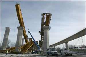 After the accident, the collapsed crane, left, is on the ground as its twin remains in place, right.