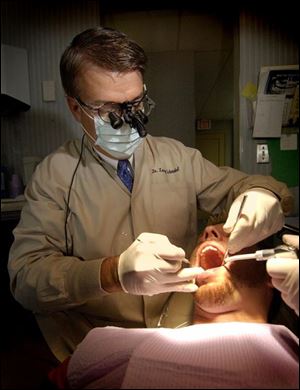 Larry P. Schmakel examines Nathan Fitzgerald in the dentist's Toledo office. Dr. Schmakel, a downtown fixture, bought the practice in the Bell Building 21 years ago.