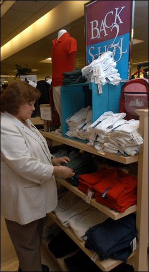 Lornezina Liburdi neatens uniforms awaiting buyers at Dillard's at Southwyck.
