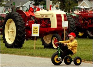Chris Durham, 6, of Liberty Center, Ohio, rides his John Deere tricycle at the Henry County Fair.