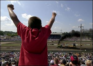 Ten-year-old Daric Euler of Bowling Green lets out a scream as he cheers a competitor during a tractor-pulling run. Racer Randy Kleikamp autographs a T-shirt worn by Bridget Sevitz, 10, of Lima, at the Wood County Fairgrounds.