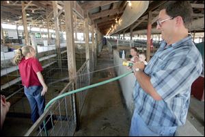 Paul Elfring playfully squirts niece McKenzie Schneider after she finishes cleaning the pigs she will be showing at the Sandusky County Fair, which opens today. 