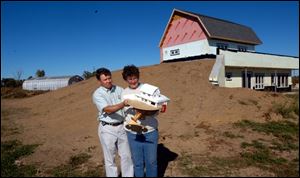 Ralph and Leah Semrock hold a model of the home they're building in Ottawa County. The home's solar panels and wind turbine will help reduce the Semrocks' energy bills.