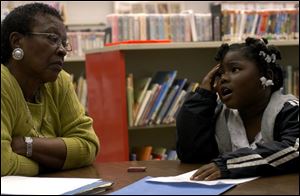 ROV Homework helpers Eboni Howell, six of Toledo, trys to decide what she will draw as part of her first grade homework assignment while homework helper Odell Chancy, a retired school teacher of 33 years, gives her some ideas. Chancy, volunteering as a homework helper for the last three years, is available at the Kent branch of the Toledo/Lucas County Public Library. Other helpers are available at branches throughout the week. Blade photo by Luke Wark
