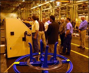 Jeff Gaietto, in short sleeves, left, a machine-builder with National Machinery LLC in Tiffin, shows a machine's operation. The manufacturer has rebounded from its near-demise.