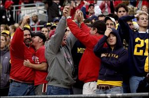 Ohio State fans Dan Fahrer, of Temperance, Mich.; Brian Dennie, an OSU student from Lambertville, Mich.; Bill Dennie (Brian's dad), and Jeff Jeckavitch of Salem, Ohio, celebrate a Buckeyes touchdown, much to the dismay of surrounding Michigan fans in Ohio Stadium.