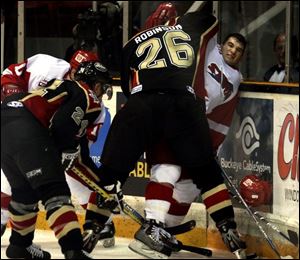 Toledo's Luc Sleigher loses his helmet after being slammed into the glass by Wheeling's Darcy Robinson.