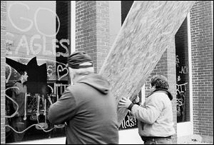 Kevin Lashaway and Steve Fiser board up a smashed cafeteria window at the high school. Teacher Dave Schaub is inside.