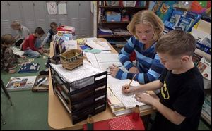 Katie Wendt, a second-grade teacher in Vanlue, works with Gage Parker, 8. Vanlue's superintendent said small schools are costlier to run on a per-pupil basis than bigger school districts.