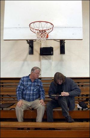 Auctioneer Jerry Robinson, left, looks on as Donald Cox signs a deal to pay $17,000 for the land and the building.