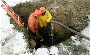 City workers Sam Loy and Sam Basil work on a broken water main on Winnette Drive during a cold Thursday afternoon.