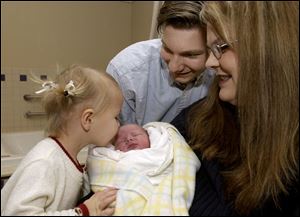 CTY newbaby02p Emily Bruhl, 3, left,  kisses her new baby brother Joshua Bruhl, as dad Steven Bruhl, and mom Laurel Bruhl look on at St. Anne's Hospital on Saturday 1/1/05.  The Blade/Dave Zapotosky