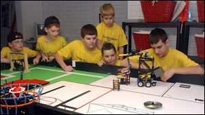 Members of the state champion Circuit Breakers from Sylvania are, from left, Brian Sherman, 10; Tyler Savino, 11; Kevin David, 13; Rowan Shaw, 10, standing; Aaron Matesz, 11, and Ian Shaw, 14, with the team's winning robot on the table.
