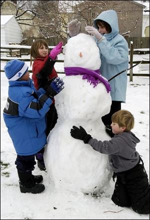 A snow day gives Arlington Elementary students, from left,
Deontae Smith, Mara Momenee, Emily Goodman, and Simon
Momenee another chance to build a snowman.
