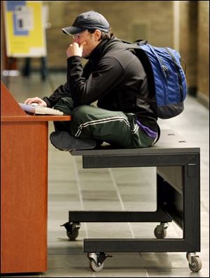 ROV Scott Dinger, 29, a third year law student at the University of Toledo, uses a wheeled cart as a makeshift chair so he can sit at a computer terminal and access the internet in the Law Center building on campus on Friday, 2/25/05.  The Blade/Dave Zapotosky