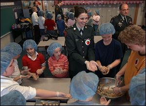NBR buckeye28p 1 Bowling Green ROTC Cadet Brittany Kull, center, helps Glenwood Elementary School students make Buckeye cookies for a fundraiser for soldiers Monday, Feb. 28, 2005. The Blade/Lori King